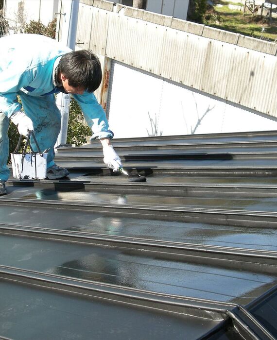 屋根の塗装作業を進める職人